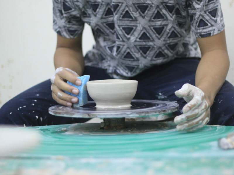 Someone tries wheel throwing and makes a clay bowl